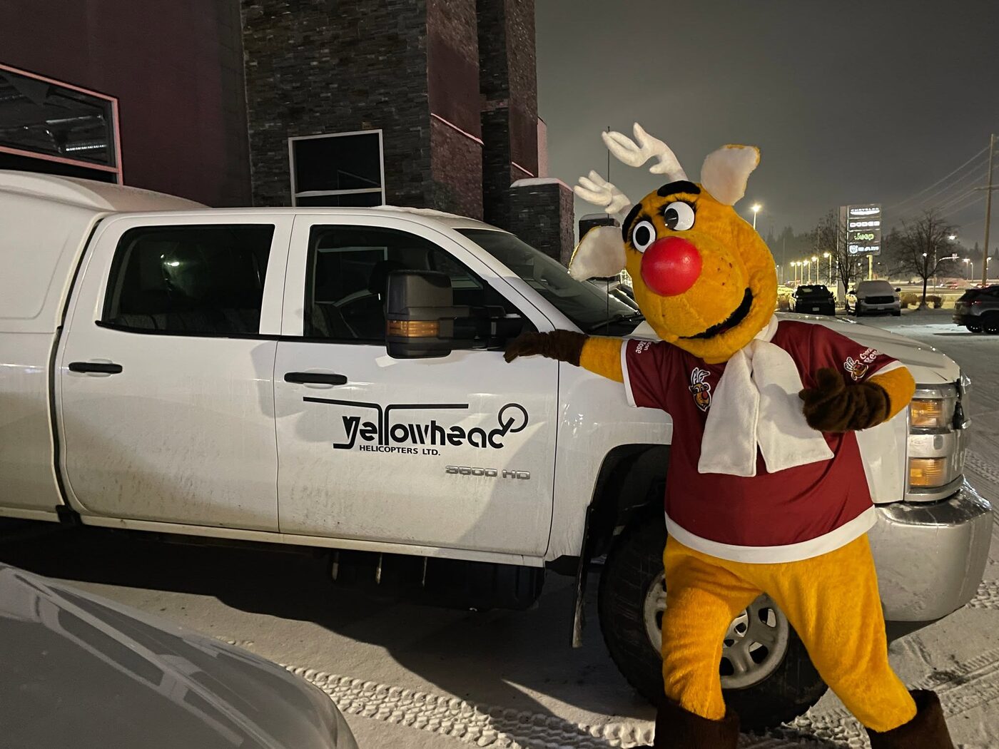 Rudy standing beside a white pickup truck on a city street at night.